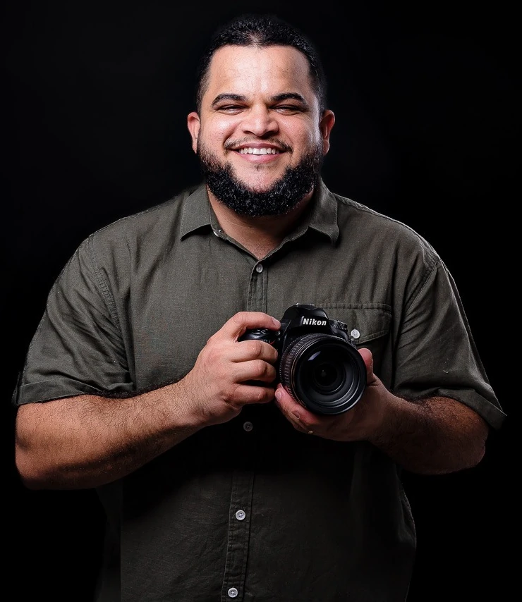 Leandro Silva, fotógrafo em Vila Velha, sorrindo e segurando sua câmera Nikon